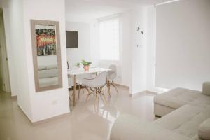 a white living room with a table and a mirror at Hermoso Apartamento en el Norte in Montería