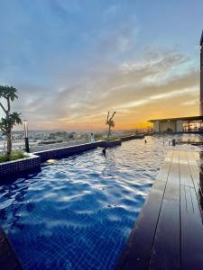 a swimming pool with a sunset in the background at Verdela Pollux Meisterstadt Batam apartement in Batam Center