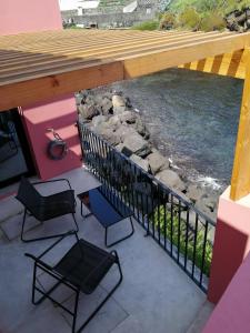 a patio with chairs and a fence and water at Terreiro Ocean House - Sea View in São Roque