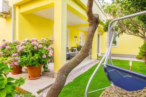 une cour avec des fleurs et une maison jaune dans l'établissement Apartman 1, à Omišalj