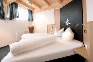 two beds in a hotel room with white sheets at Haus Kristall in Serfaus