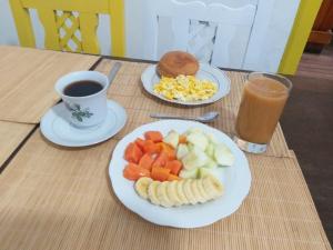 uma mesa com dois pratos de fruta e uma chávena de café em Galapagos Natural Life Hostel em Quito