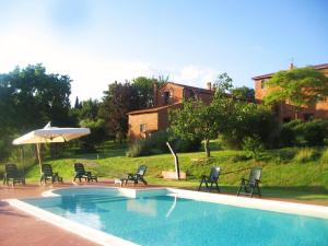 a swimming pool with chairs and an umbrella at Agriturismo Borgo Del Papa in Badia