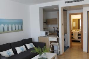 un soggiorno con divano nero e una cucina di Paseo Maritimo a Málaga