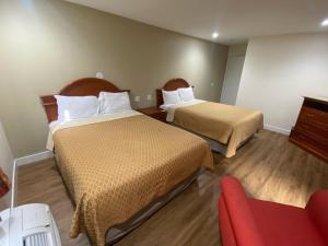 a hotel room with two beds and a red chair at Royale Inn Motel in Whittier