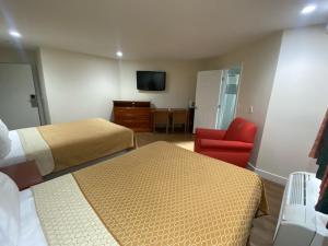 a hotel room with two beds and a red chair at Royale Inn Motel in Whittier