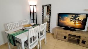 uma sala de jantar com uma televisão e uma mesa e cadeiras brancas em Villa del Sol em Gran Alacant