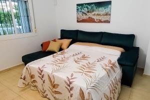 Cama en habitación con sofá azul en Villa del Sol, en Gran Alacant