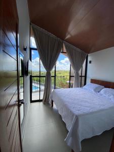 een slaapkamer met een bed en een groot raam bij CHALE VILAALICE in Monte das Gameleiras