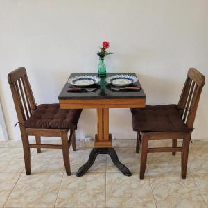 una mesa de madera con 2 sillas y un jarrón con una flor en HospedaCopa 1202 - Vista Lateral Mar, en Río de Janeiro