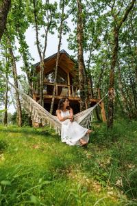 een vrouw in een hangmat voor een boomhut bij Wabi sabi lodge&spa in Turenne