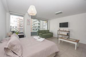 - une chambre blanche avec un lit et un canapé vert dans l'établissement Libertador Complete Suite, à Buenos Aires