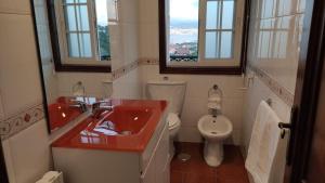 a bathroom with a red sink and a toilet at Os piñeiros vacacional in Moaña +12 photos
