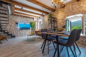 a dining room with a stone wall and a table and chairs at Villa Le Adria - Private HotTub - Free Beach Parking in Kozica