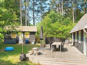 una terraza de madera con mesa y sombrilla en 6 person holiday home in Nyk bing Sj en Rørvig