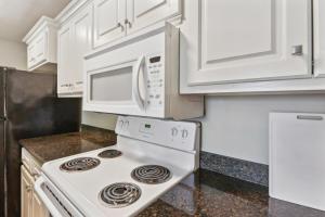 a kitchen with white cabinets and a stove with a microwave at Lovely Lake Charles Duplex in Central Location! in Lake Charles