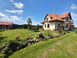 a house with a grassy yard with flowers and a yard at Dom Gościnny u Szymona in Wrzosowo