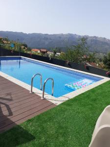 a swimming pool with a green lawn and mountains in the background at Casa dos Mirandas in Vieira do Minho