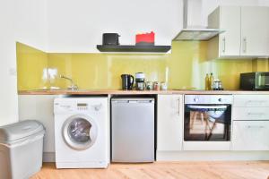 a kitchen with a washing machine and a washer at Princess Lofts City Centre Studios with Nespresso Coffee Machines By StayRight in Swansea