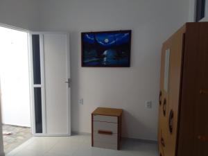 a room with a white wall with a picture on the wall at Casa do Bruno - Apartamento terreo - 1 - Terra - Quarto e sala com cozinha americana na praia do preá-CE in Prea