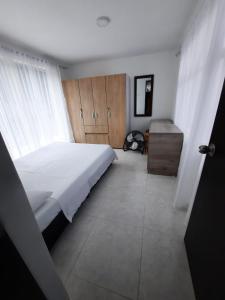 een slaapkamer met een groot wit bed en een houten kast bij CASA VACACIONAL Babilonia in Girardot