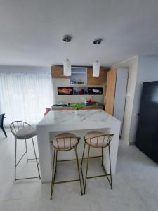 a kitchen with a white counter and two chairs at CASA VACACIONAL Babilonia in Girardot +27 photos