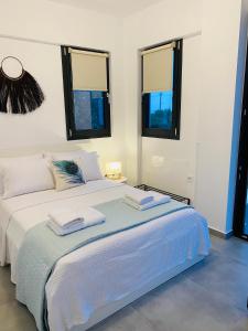 ein weißes Schlafzimmer mit einem Bett mit zwei Handtüchern darauf in der Unterkunft Casa al Mare in Nea Roda