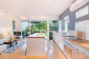 Short Stroll to White Sandy Beach في ساحة كاسوارينا: مطبخ مع دواليب بيضاء وغرفة معيشة +3 صور