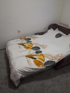 Una cama con una manta blanca con hojas. en Devetka, en Pirot