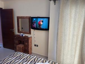 1 dormitorio con TV en la pared y 1 cama en أشقار طنجة, en Jbila