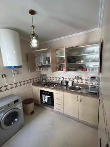 a kitchen with a sink and a washing machine at أشقار طنجة in Jbila