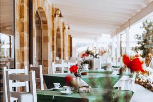 - une table verte avec des chaises blanches et des fleurs rouges dans l'établissement Masseria Pisciani, à Torchiarolo