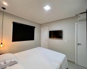 - une chambre avec un lit blanc et une télévision à écran plat dans l'établissement Apto Próximo ao Shopping, à Foz do Iguaçu