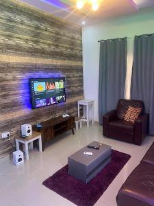 Il comprend un salon doté d'une télévision à écran plat et d'un canapé. dans l'établissement Rahims 3 bedroom Bungalow - Dalaba, à Jarbang