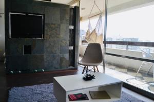 a living room with a tv and a table and a chair at Departamento muy central, a pasos de playa, bares y terminal in Viña del Mar