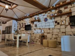 a room with a stone wall with a table and chairs at Kerme Ottoman Alacati in Alaçatı