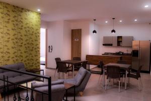 a living room with tables and chairs and a kitchen at Ayenda Hotel MM in Pereira