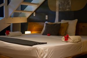 Una cama con sábanas blancas y flores rojas. en Afreeka Beach Hotel, en Las Terrenas