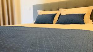 ein Bett mit zwei blauen Kissen und einer grauen Bettdecke in der Unterkunft School Motorhome Park in Óvoa + 5 Fotos