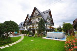 a house with a swimming pool in the yard at Apartamenty Willa Anna in Poronin