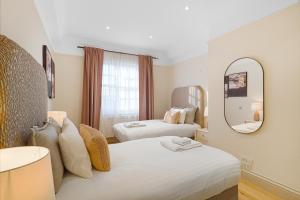 a hotel room with two beds and a mirror at Spacious and Modern 4 beds home in Kensington in London