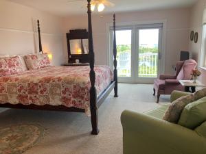 een slaapkamer met een bed, een stoel en een bank bij Payne's Harbor View Inn in New Shoreham