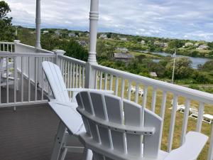 twee witte stoelen op een veranda met uitzicht op een rivier bij Payne's Harbor View Inn in New Shoreham