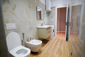 a bathroom with a white toilet and a sink at Klei’s Daily Apartment in Tirana