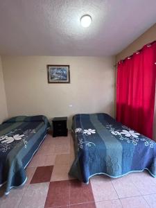 イスミキルパンにあるHotel Antonioの赤いカーテンが備わるドミトリールームのベッド2台分です。
