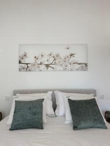a white bed with white pillows and a picture of flowers at Horta dos Cedros in Tomar +78 photos