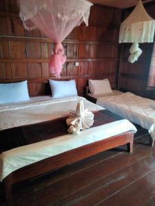 a room with two beds and a stuffed animal sitting on top at Riverside Bungalow Don Det in Don Det