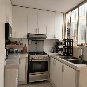 利马Casa Cultura的厨房配有白色橱柜、炉灶和水槽。
