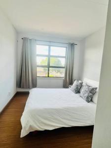 a bedroom with a large white bed with a window at 2 Bedroom, Clutter free in Pretoria