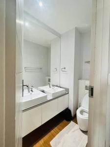 a white bathroom with two sinks and a toilet at 2 Bedroom, Clutter free in Pretoria